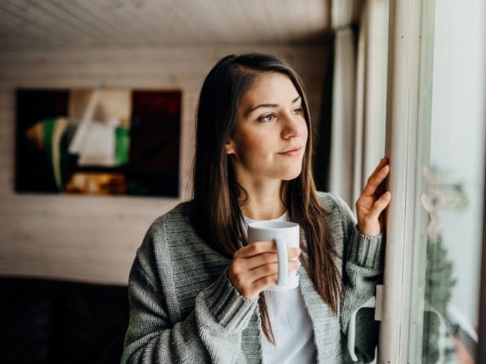 Young woman in quarantine looking out the window